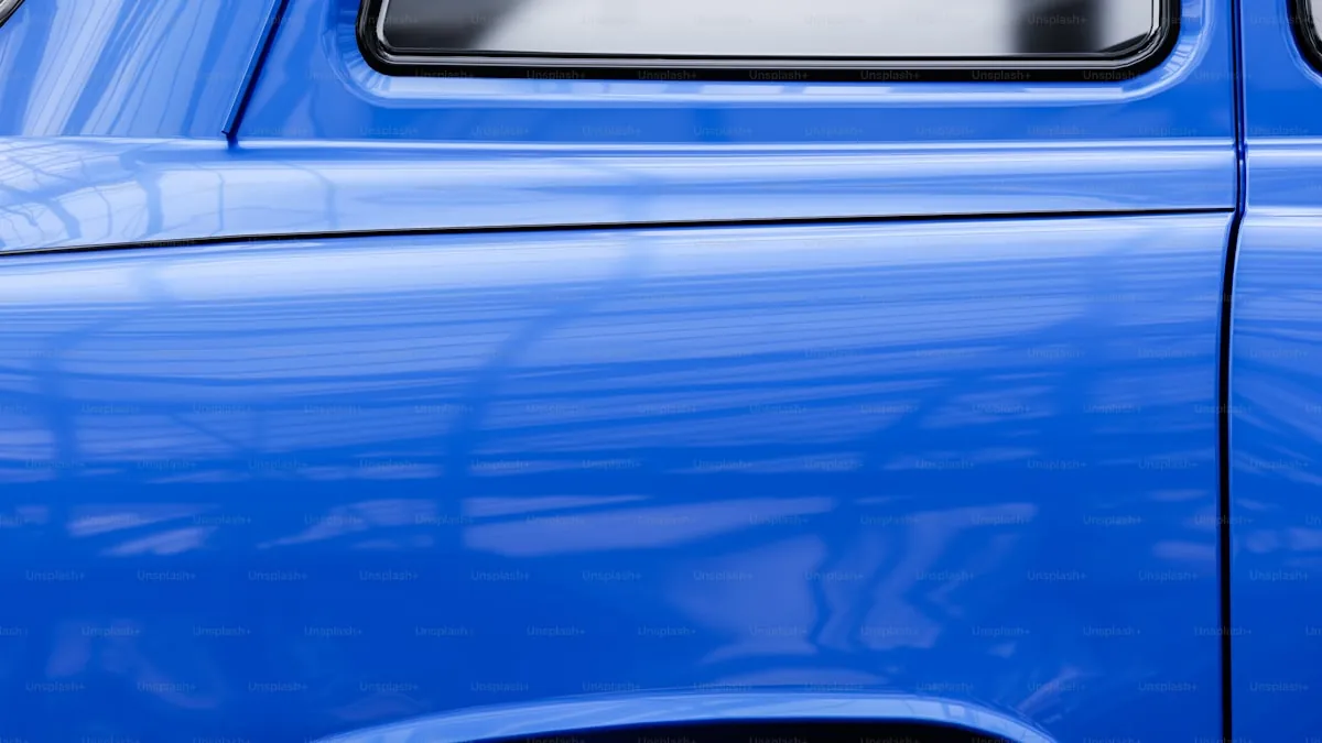 Technician polishing a dark-colored car panel under bright workshop lighting
