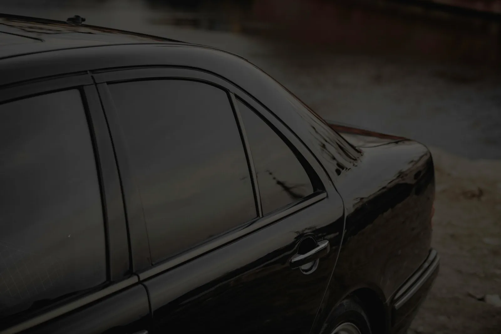 close-up of swirl marks on a dark gray car panel under direct light