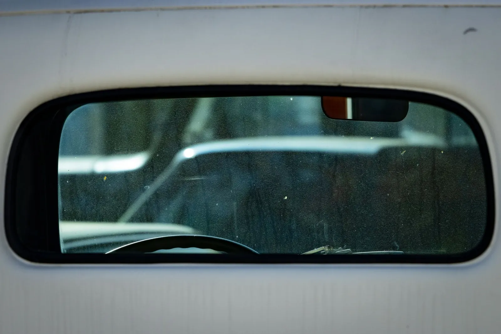 Close view of a rear car window with defroster lines visible through dark tint film